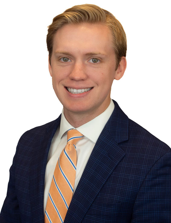 Bradley Davis Professional headshot: smiling man in a navy suit and orange striped tie, white shirt, neutral background